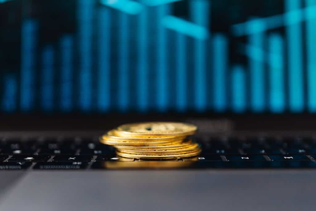 Stack of Gold Coins on a Laptop Displaying a Graph