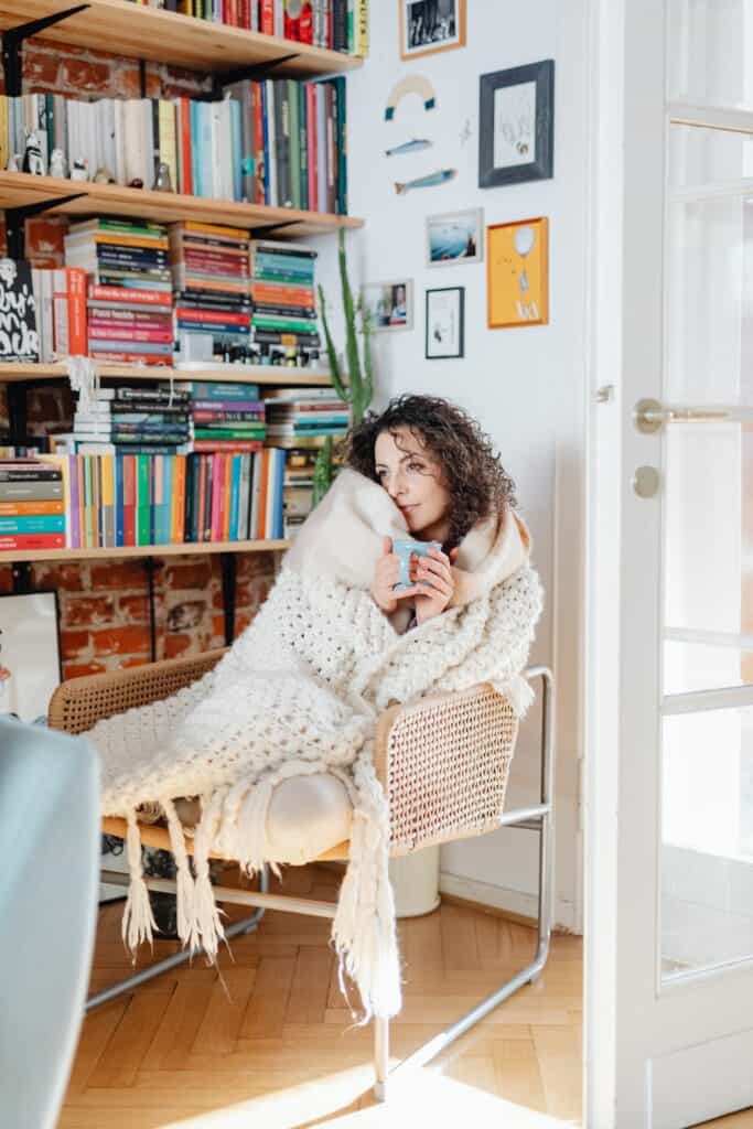 Woman Wrapped in a Cozy Blanket Holding a Mug