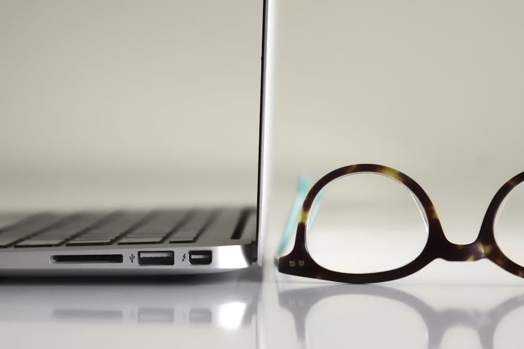 Black Framed Eyeglasses Beside Laptop Computer